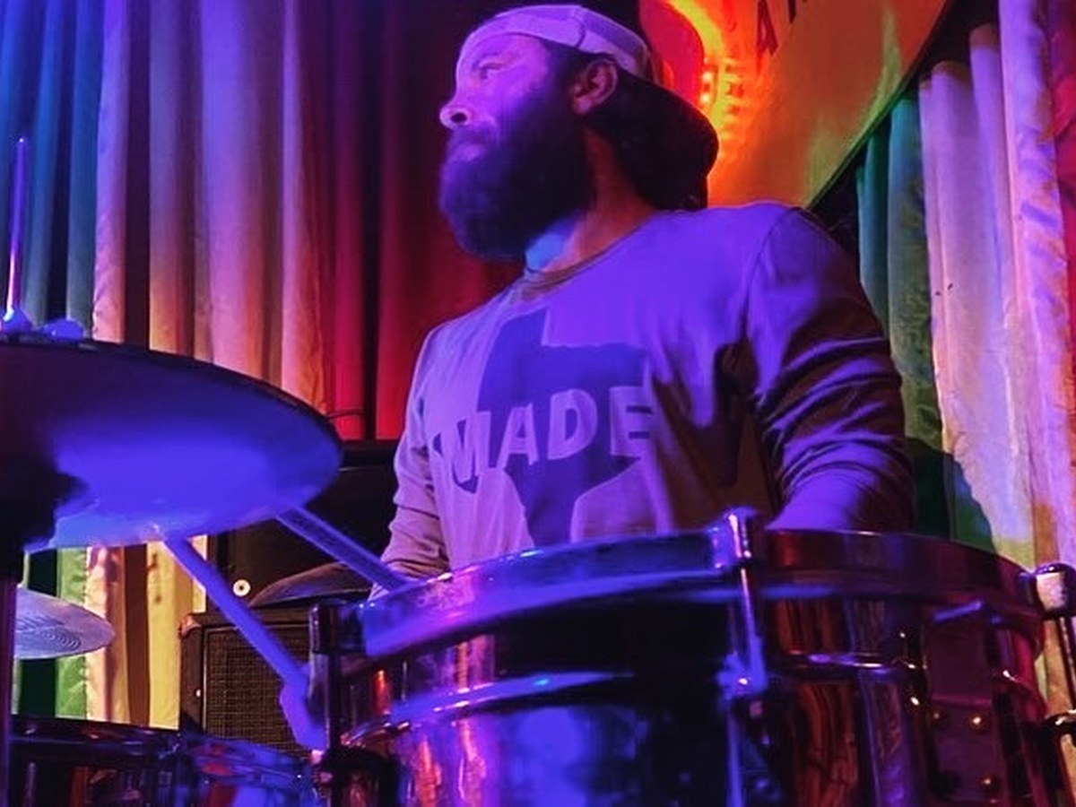 Drummer at kit under purple lighting