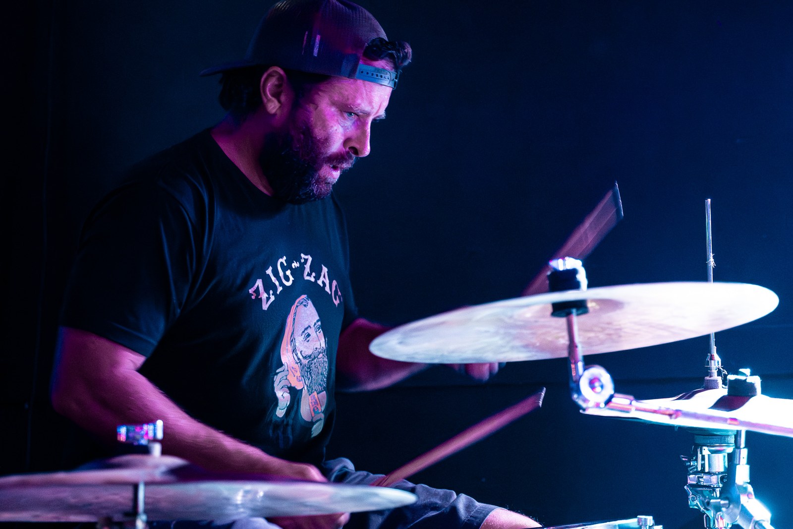 Drummer playing cymbals in blue stage light