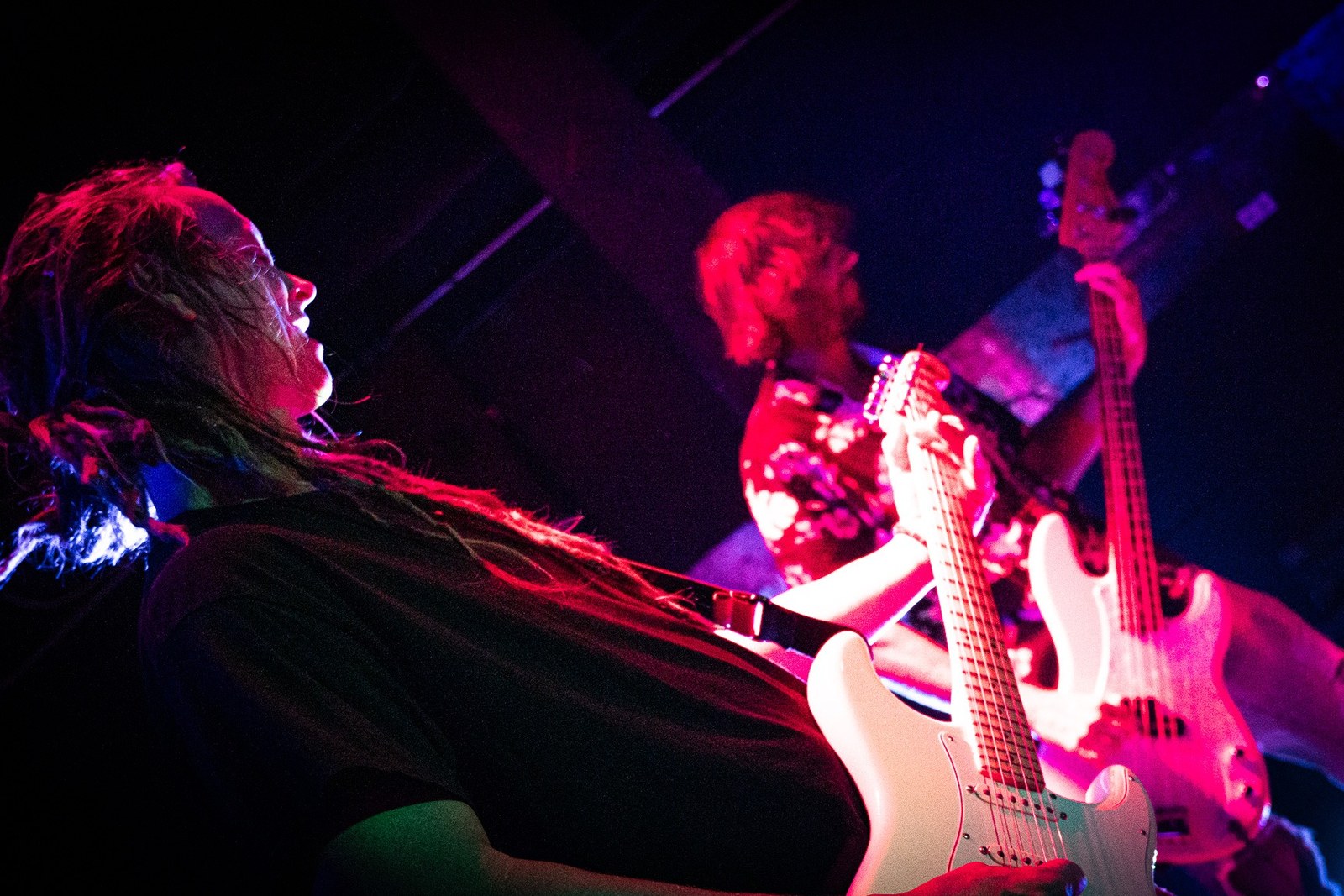 Guitarist and bassist playing under red stage lights