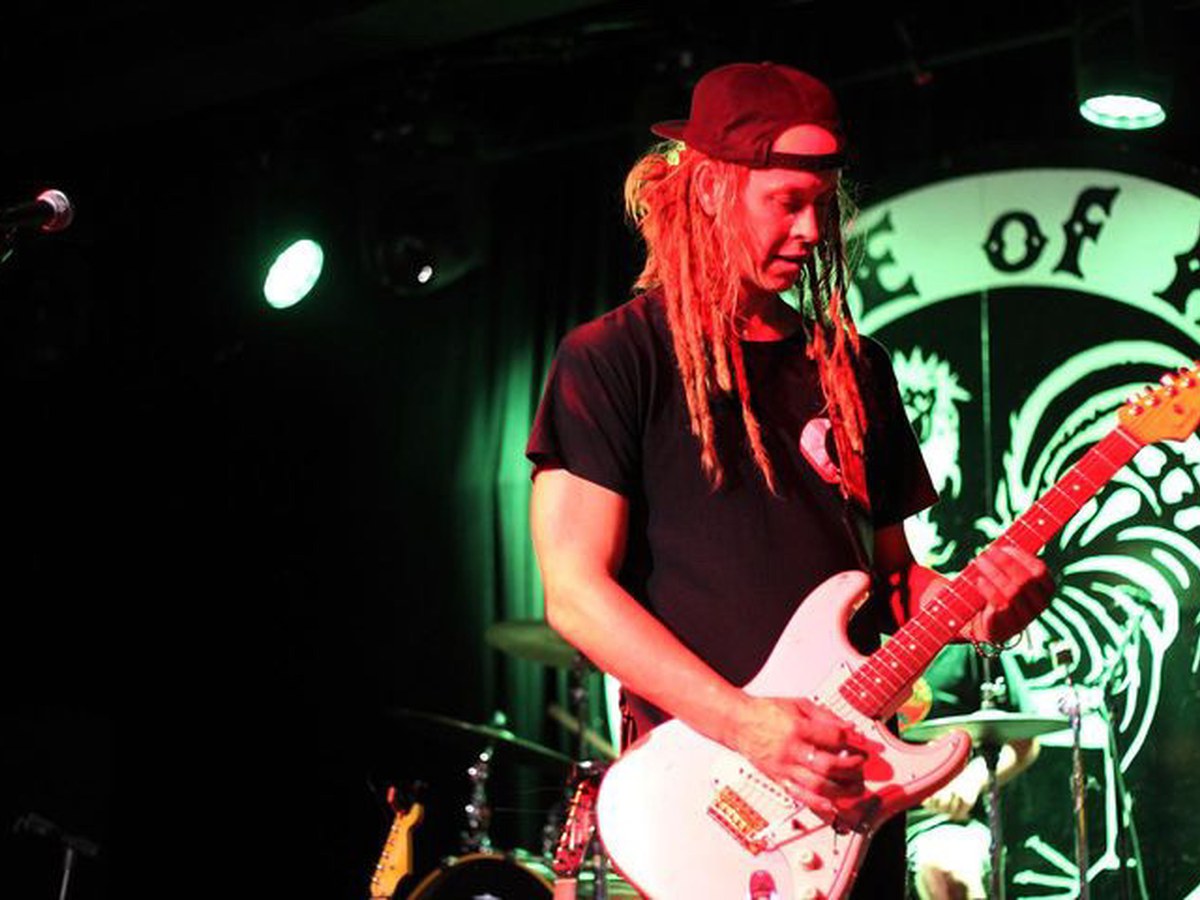 Guitarist playing a white guitar under green and red lights